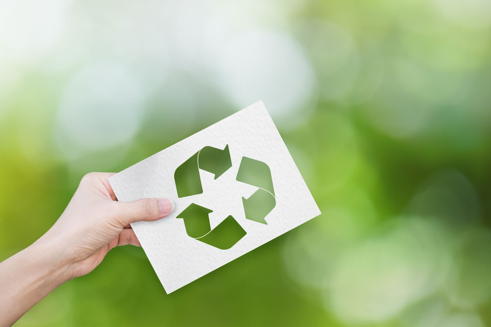 Person holding a piece of paper with the recycling symbol on it. 
