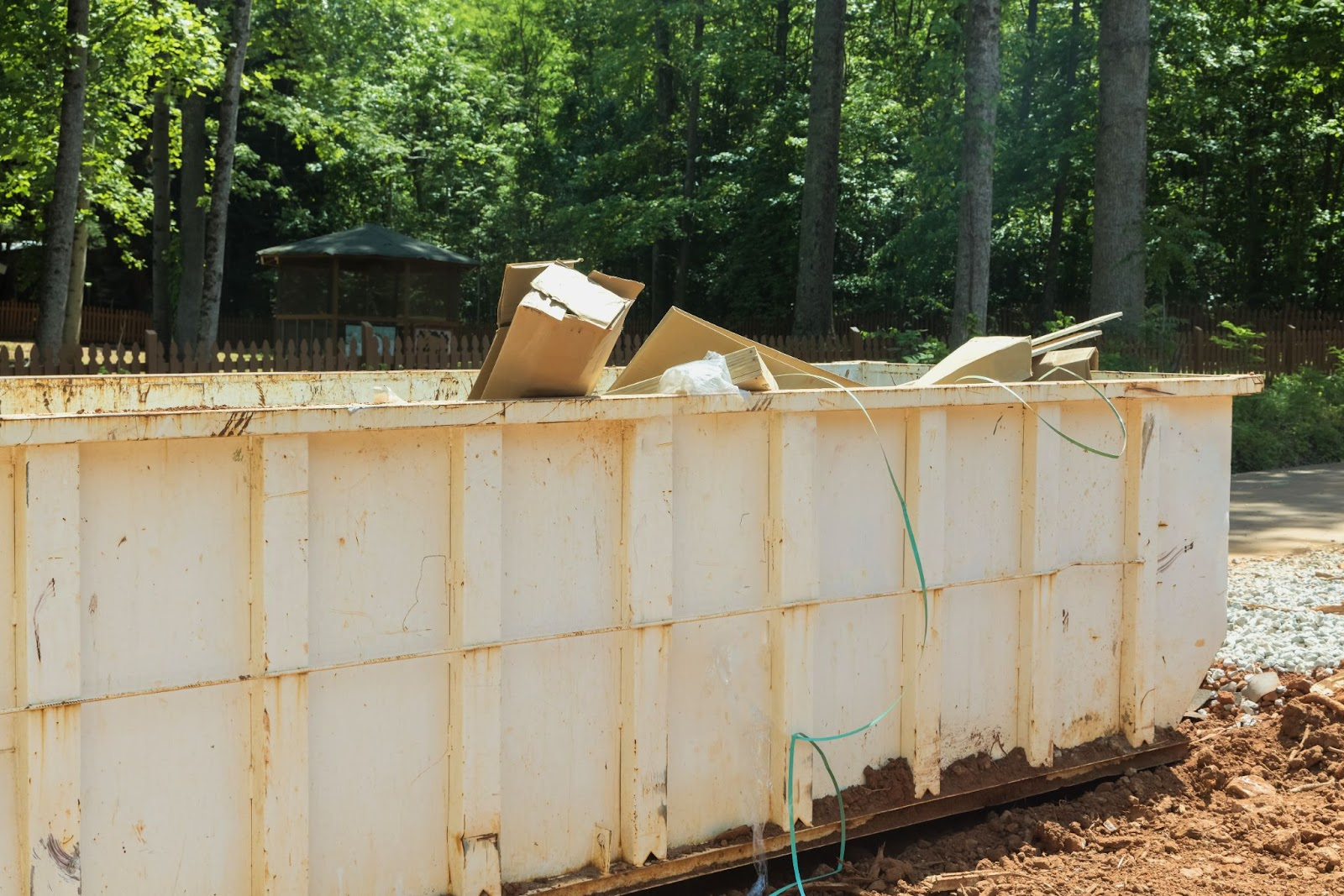 A white dumpster filled with recyclable construction waste and debris.