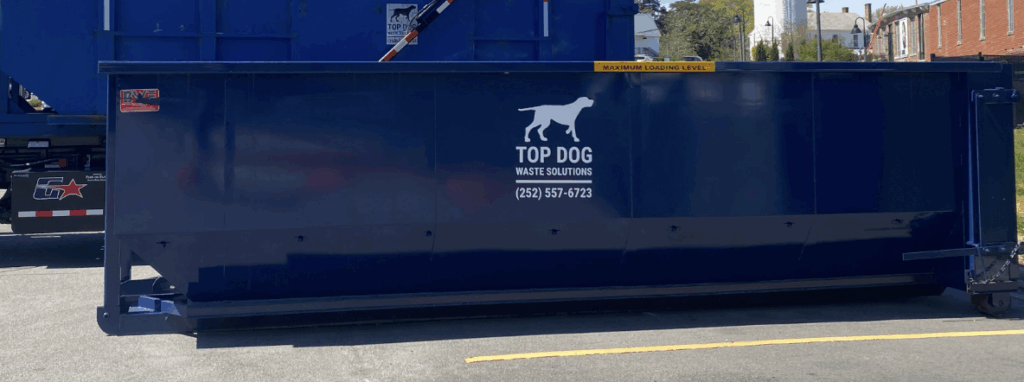 Dumpster next to a trash truck in a parking lot. 