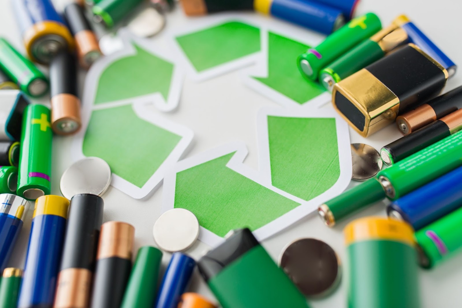 Used batteries surrounding a recycling sign representing Universal Waste disposal