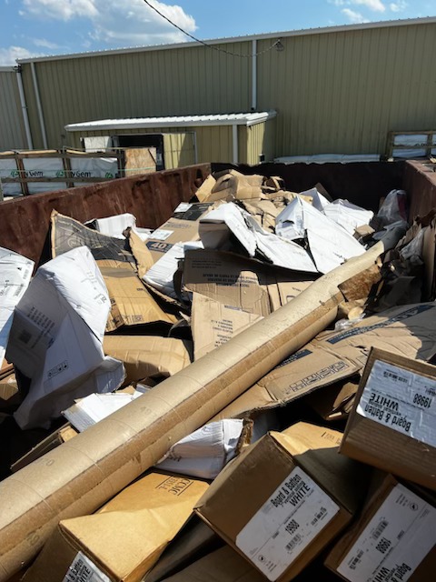 A large dumpster filled with paper and cardboard waste from a commercial facility