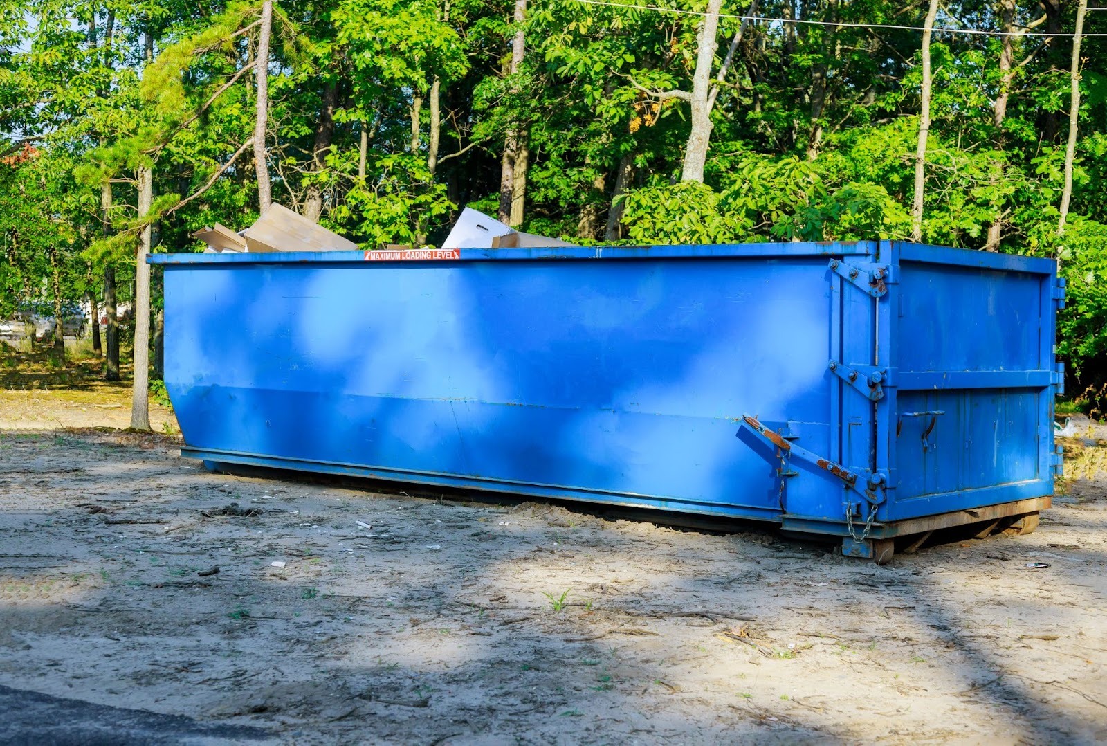 A large blue dumpster sitting at its rental site.