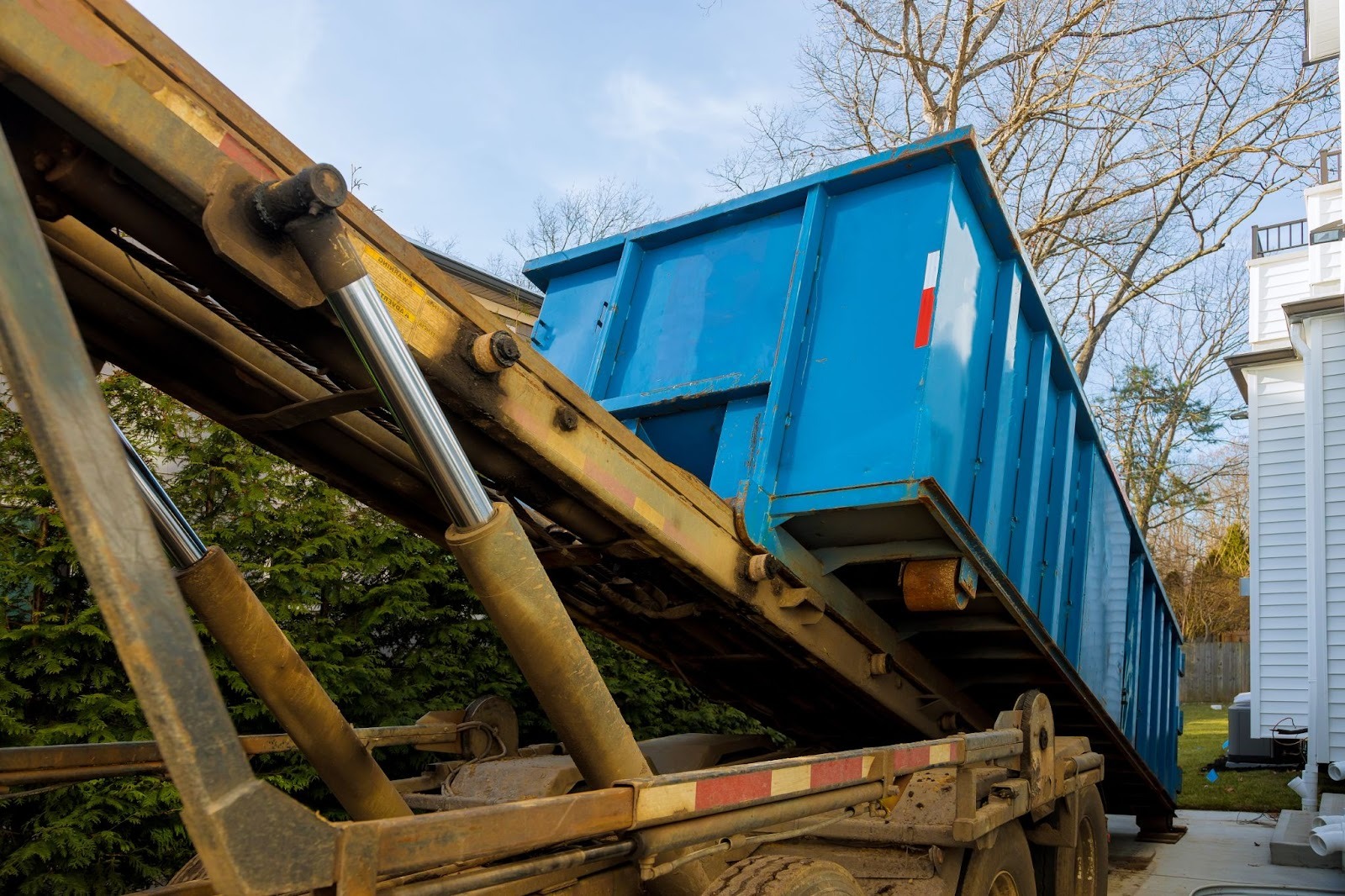 An empty dumpster is unloaded onto a commercial property.