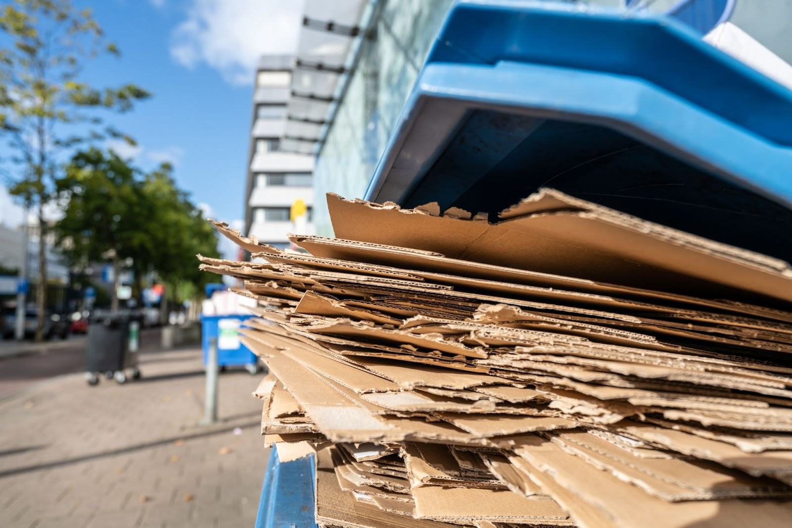 Flattened used commercial cardboard boxes in a plastic bin for paper recycling.