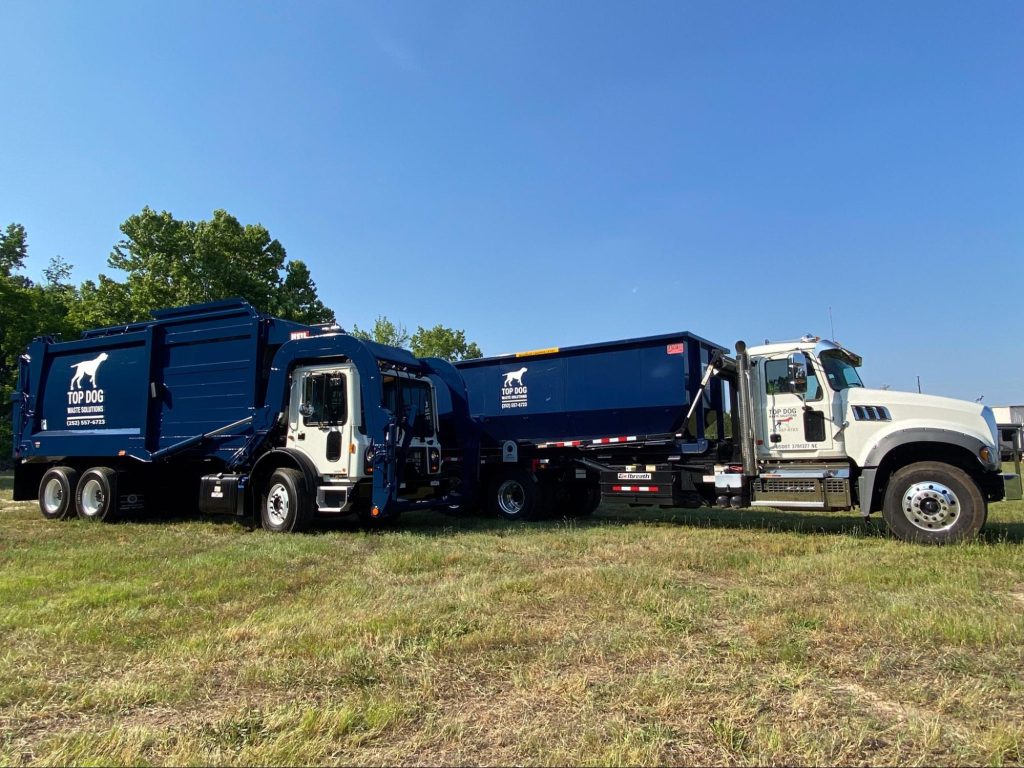 Garbage trucks parked on a lawn.